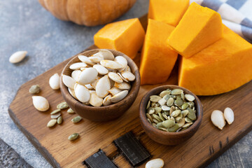 Raw superfoods pumpkin seeds after harvest. Pumpkin seeds in wooden bowl over gray stone background.
