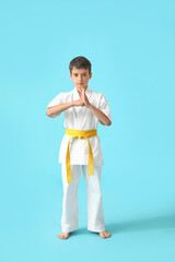 Little boy practicing karate on color background