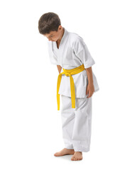 Little boy performing ritual bow before practicing karate on white background