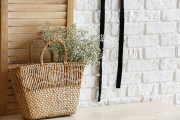 Wicker bag with beautiful gypsophila flowers on table in room