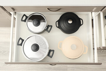 Different cooking pots in open kitchen drawer, closeup