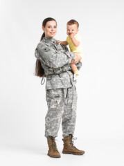Female soldier with her little son on light background