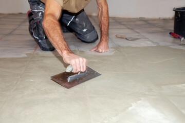 Construction worker leveling compound with putty knife. Renovation, floor leveling screed, mass...