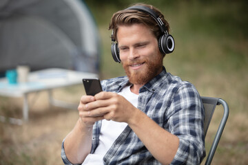 young man listening to music while camping