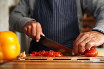 Close up of hands, elderly multi-cultural male chopping up vegetables for breakfast. Retired,...