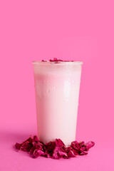 Glass of tasty rose latte on color background