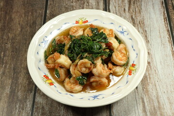 Famous spicy fried fresh peel shrimp with hot basil and chilly serving on the plate. 