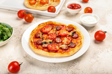 Plate with delicious mini pizza and sauces on light background