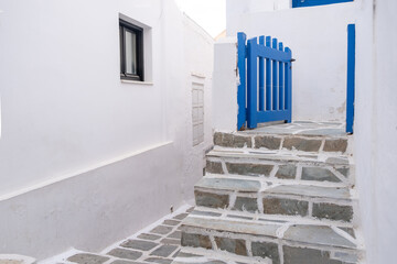 Cyclades, Greece. Ios, Nios island, Chora. White building, stone paved stairs and blue gate open,