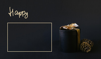 Black gift box with golden bow on black background for christmas and new year concept