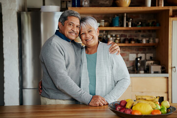 Portrait of happily retired elderly biracial couple holding each other. Healthy lifestyle, standing in modern kitchen. - Powered by Adobe