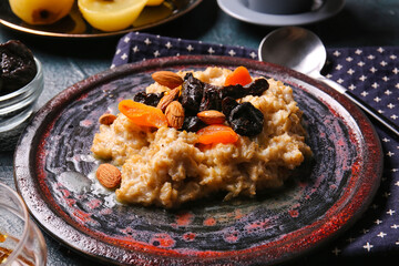 Plate with sweet oatmeal, prunes, dried apricots and almond nuts on table, closeup