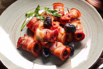 Plate with tasty prunes baked in crispy bacon and parsley, closeup