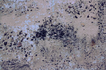 Rough gray dry concrete wall surface interspersed with small black crushed pebbles close up industrial texture for background 