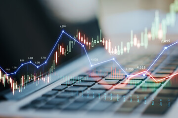 Close up of laptop computer with glowing forex chart trading interface on blurry background....