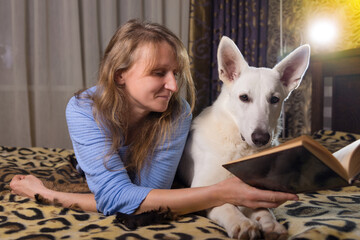 A woman lying on bed and reading a book