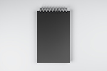 Top view and close up of black spring notepad on white desktop background. Mock up place for your advertisement. Education, work, supplies and stationery concept. 3D Rendering.