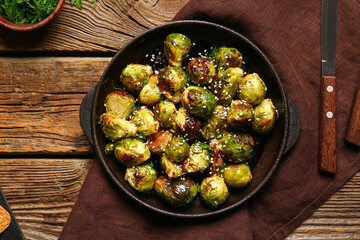 Frying pan with tasty roasted Brussels cabbage on wooden background