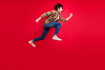 Photo of pretty charming young gentleman wear plaid outfit smiling jumping high running fast isolated red color background
