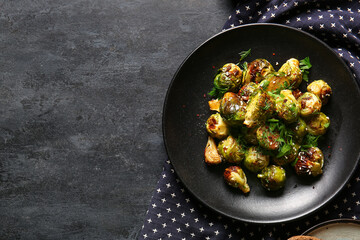 Plate with tasty roasted Brussels cabbage on dark background
