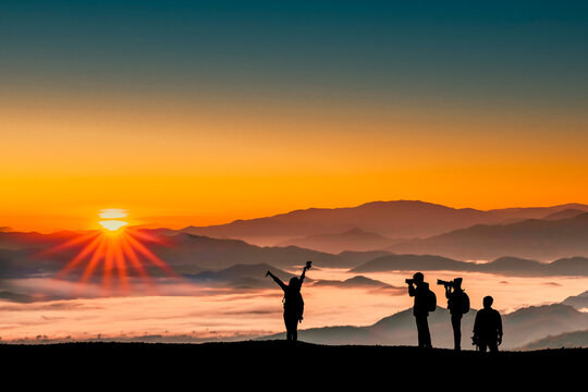 Silhouette image of traveler men and women taking photos with sunrise in the morning on mountains natural background.