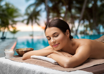 wellness, beauty and relaxation concept - young woman lying at spa over tropical beach background in french polynesia