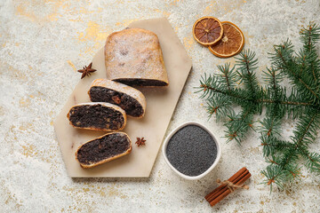 Board with cut poppy seed strudel on light background