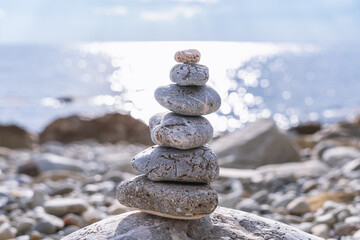 Pyramid of sea pebbles on the background of a sunny path at the sea