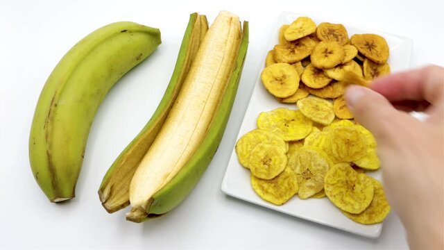 Patacones in white plate and background, recipe of fried green male banana chips