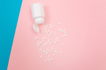 Global Pharmaceutical Industry and Medicinal Products - White Pills or Tablets Scattered from the Pill Container, Lying on Split Blue and Pink Background