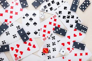 Playing cards, dominoes and dice for board games on light table. View from above.