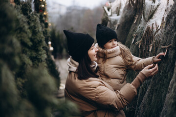 Winter holidays and people concept - happy morther and little daughter choosing christmas tree at...