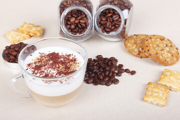Cup of cappuccino, cookies, crackers and coffee beans on table.