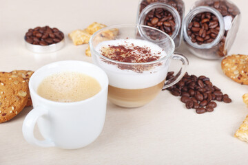 Still life with cup of espresso, cappuccino with chocolate crumbs, cookies, crackers and coffee beans on table.