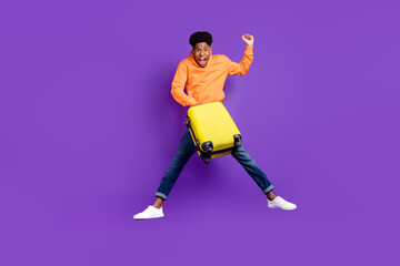 Fototapeta na wymiar Full length body size view of attractive trendy cheery lucky guy jumping holding bag isolated over bright violet purple color background