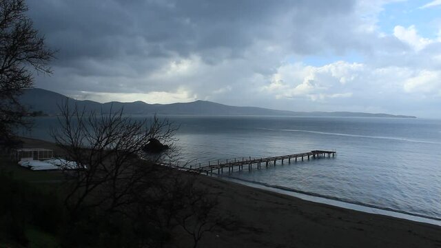 Pier on the beach. Cool day. Video taken in iskele burhaniye balikesir aegean sea coast line turkey anatolia asia. Calm cloudy rainy weather day in winter 14th december 2021.