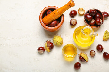 Composition with essential oil and fresh chestnuts on light background