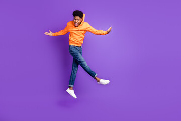 Fototapeta na wymiar Full body photo of brown haired young dark skin happy man wear jeans jump up hands winner isolated on purple color background