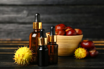 Bottles of essential oil and chestnuts on dark wooden background