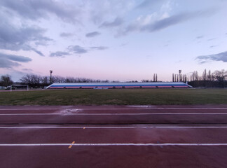 Running tracks and tribunes in the stadium in evening in winter