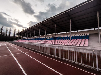 Fototapeta na wymiar Running tracks and tribunes in the stadium in evening in winter