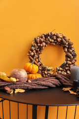 Beautiful acorn wreath, pumpkins and candles near orange wall