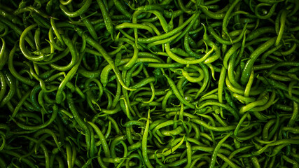 Close-up on a shelf with green peppers in the market.