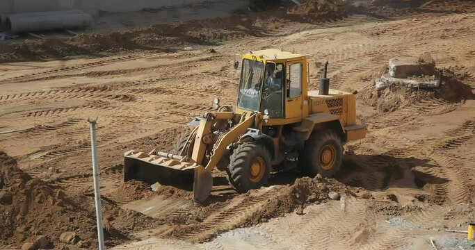 Large excavator compacts rubble. Levelling driveway. Building site. Tractor bulldozer drives close-up. Front-end loader using bucket.