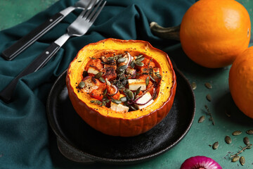 Frying pan with tasty stuffed pumpkin on green background