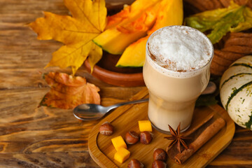 Glass of tasty pumpkin latte on wooden background