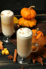 Glass cups of tasty pumpkin latte on dark wooden background