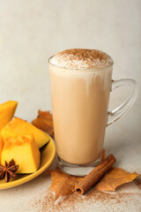 Glass cup of tasty pumpkin latte on light background