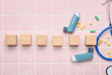 Blank wooden cubes, pills, stethoscope and asthma inhalers on color background