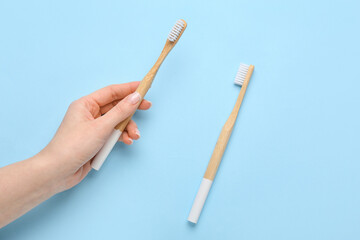 Female hand and toothbrushes on blue background